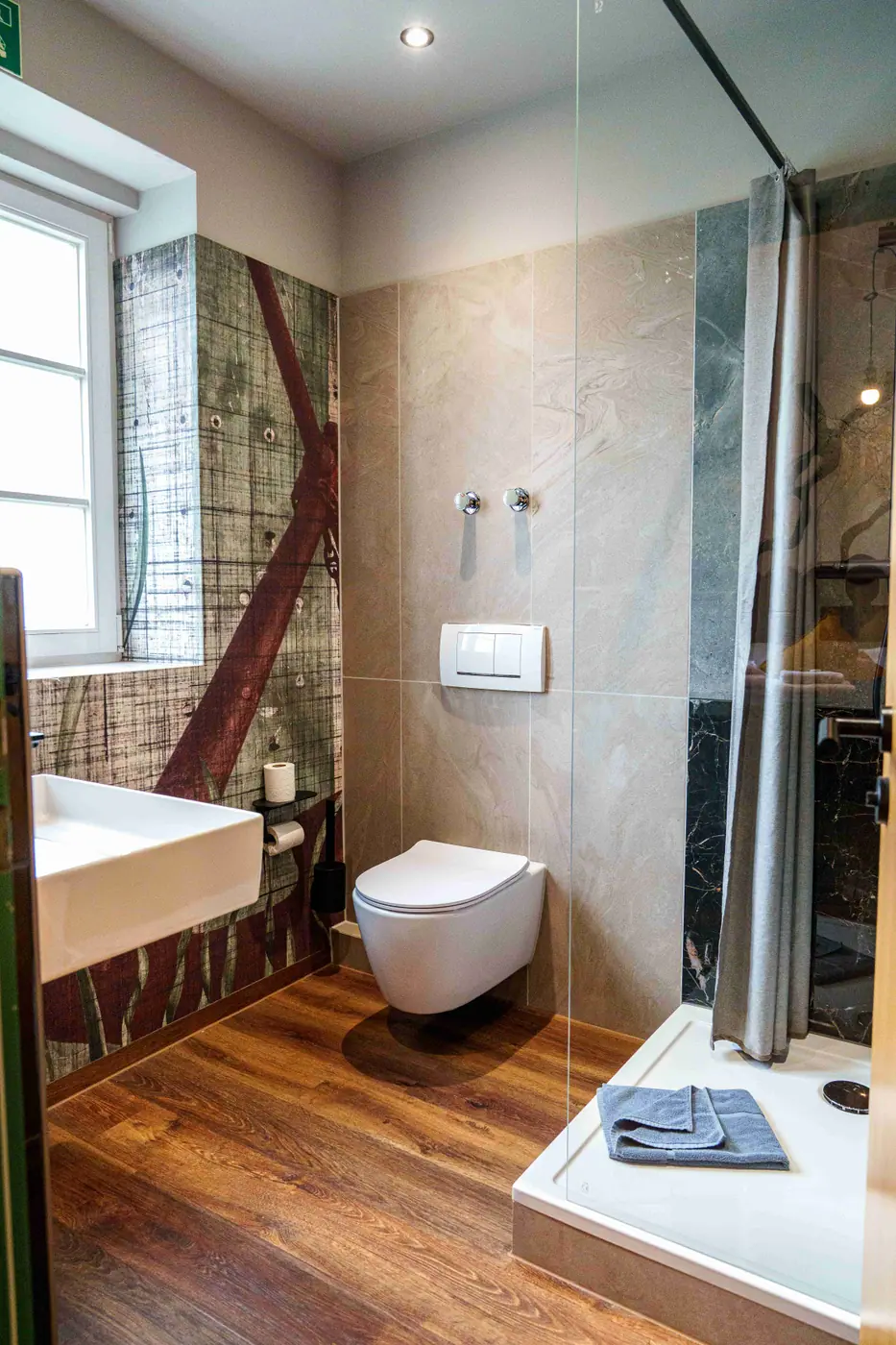 Badezimmer im Mezzotel mit Dusche, Wand-WC und Natursteinfliesen