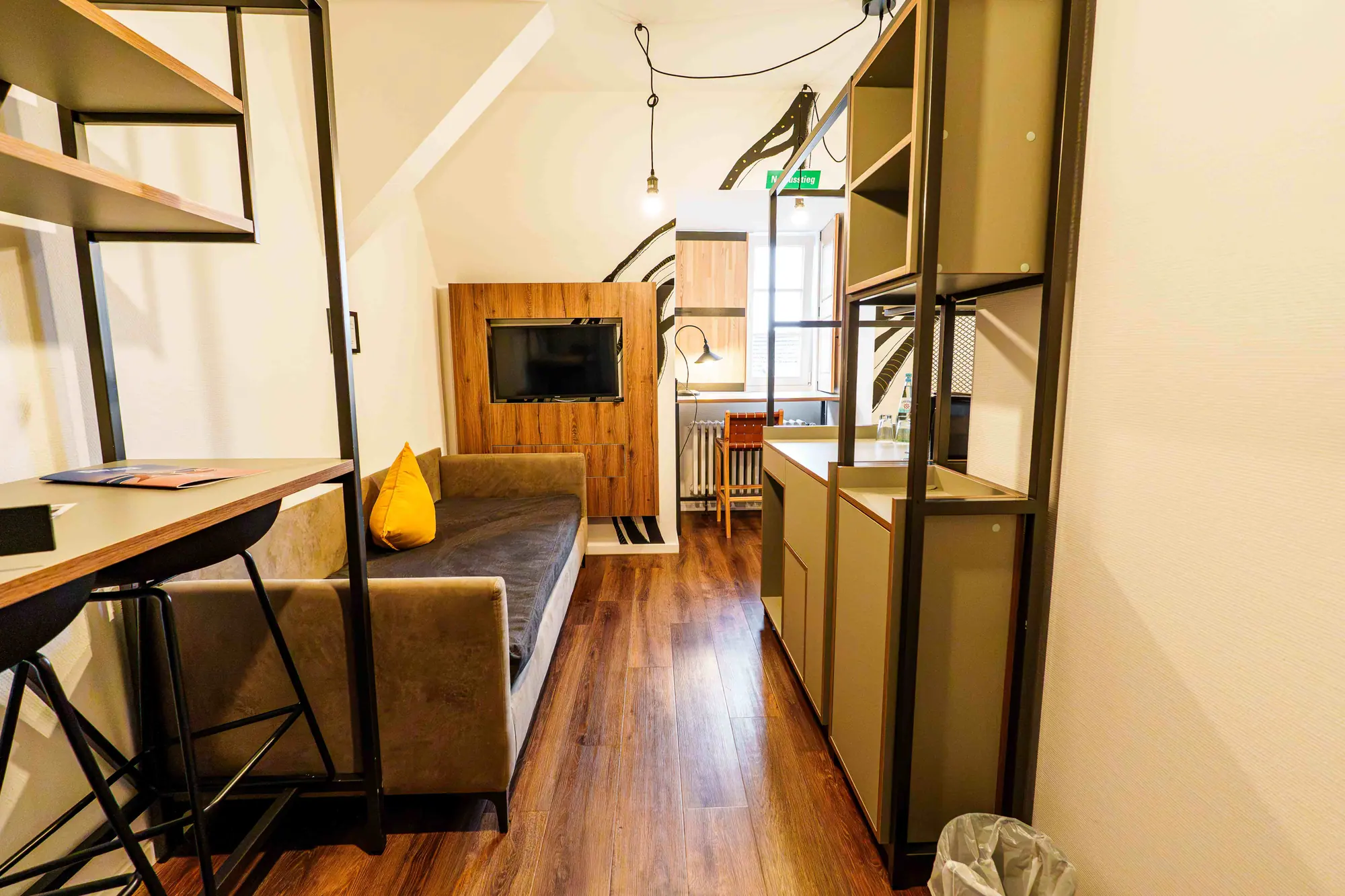 Mezzotel Zimmer mit Sofa, Hochtisch, Kaffeestation und Fenster im Hintergrund